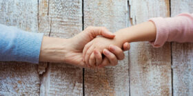 Unrecognizable mother and her daughter holding hands.