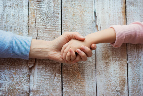 Unrecognizable mother and her daughter holding hands.